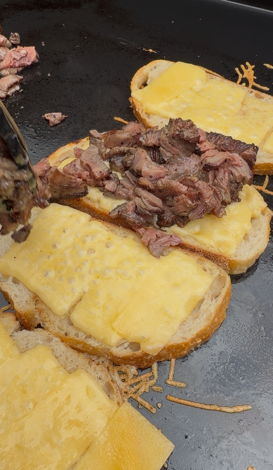 Smoked ribeye cap layered onto melted Gouda cheese on toasted sourdough to build a French Onion Steak Melt.
