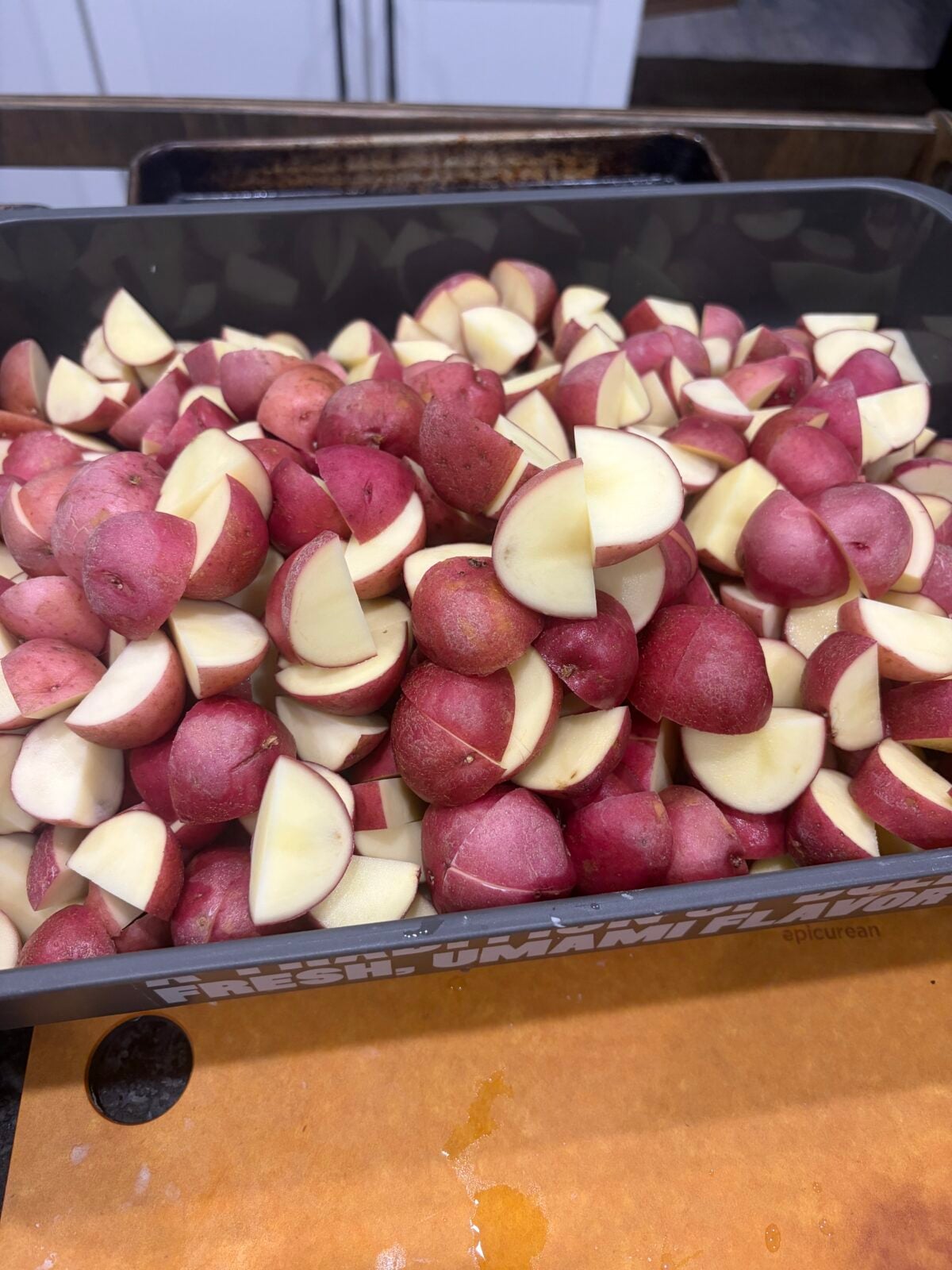 Fresh red potatoes cut into evenly sized quarters and ready to be seasoned for grilling.